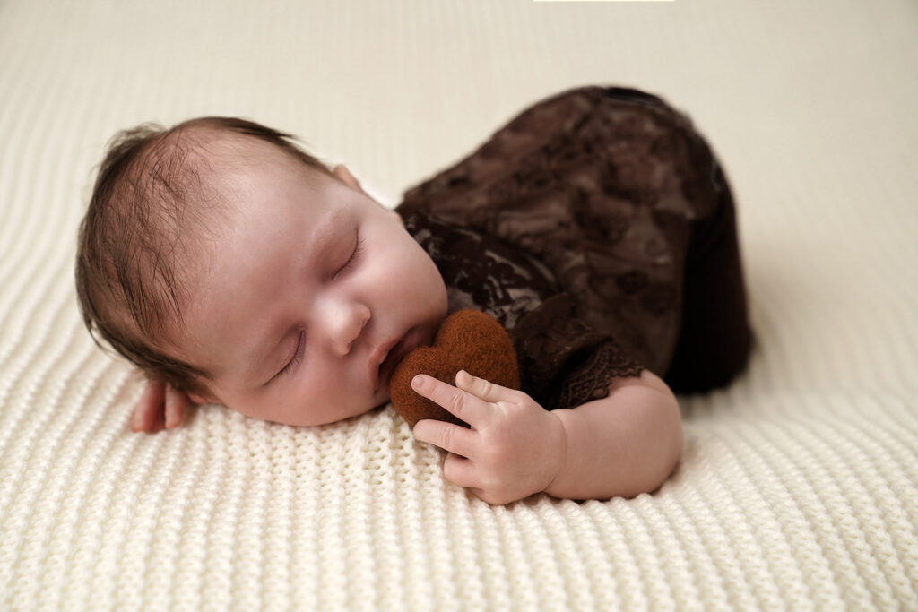 Neugeborenes mit Herzchen auf Wolldecke