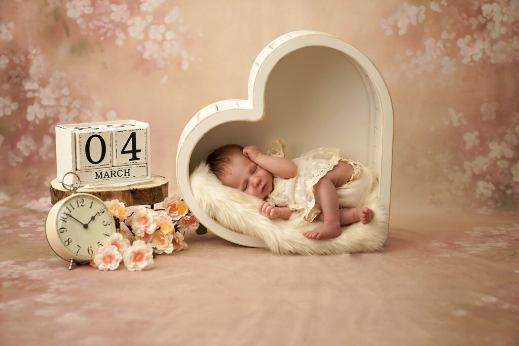 Neugeborenes im weißen Herz mit Uhr und Datumswürfel