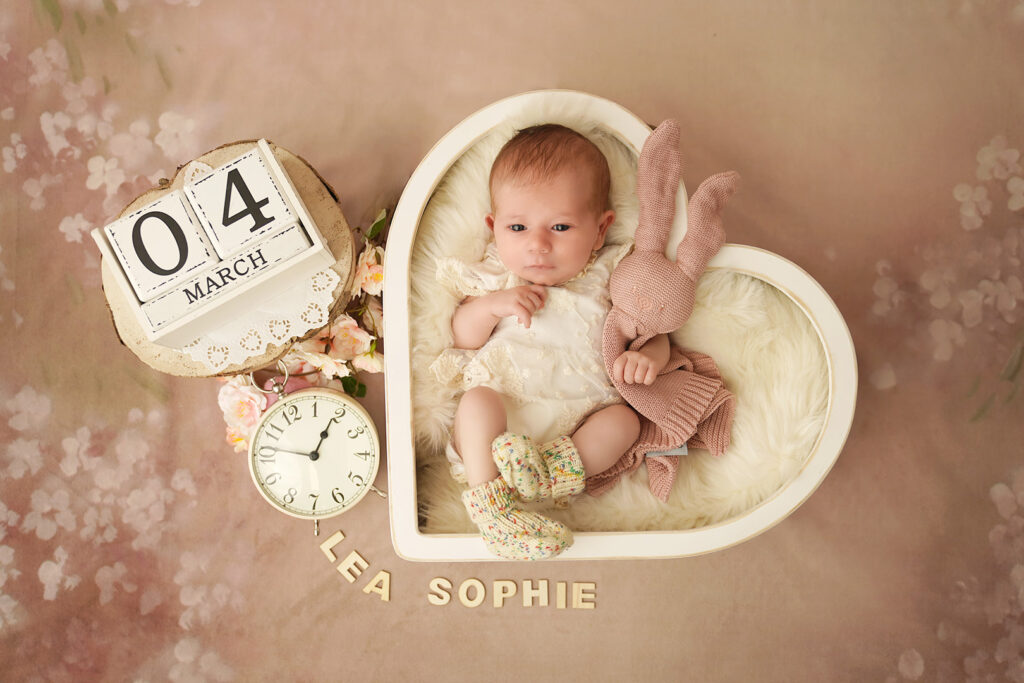 Neugeborenes im weißen Herz mit Uhr und Datumswürfel